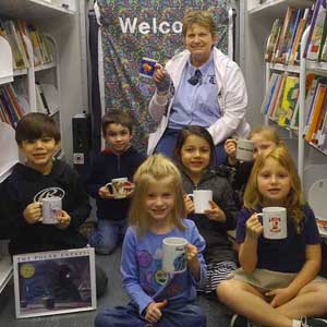 storytime children and reader with hot chocolate mugs in the library